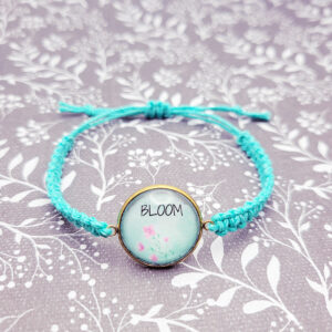 Handmade Bloom bracelet with floral charm on turquoise hemp cord styled on soft floral background, faith inspired jewelry