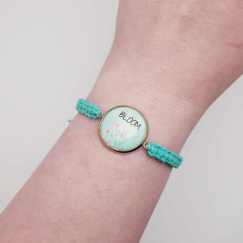 Bloom charm bracelet worn on wrist, turquoise hemp cord adjustable handmade faith bracelet with floral design