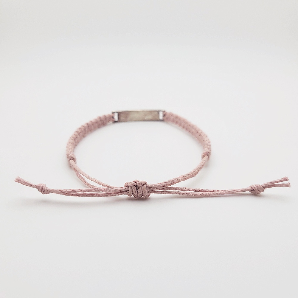 Adjustable sliding knot closure on handmade blush cord bracelet with silver inspirational word charm.