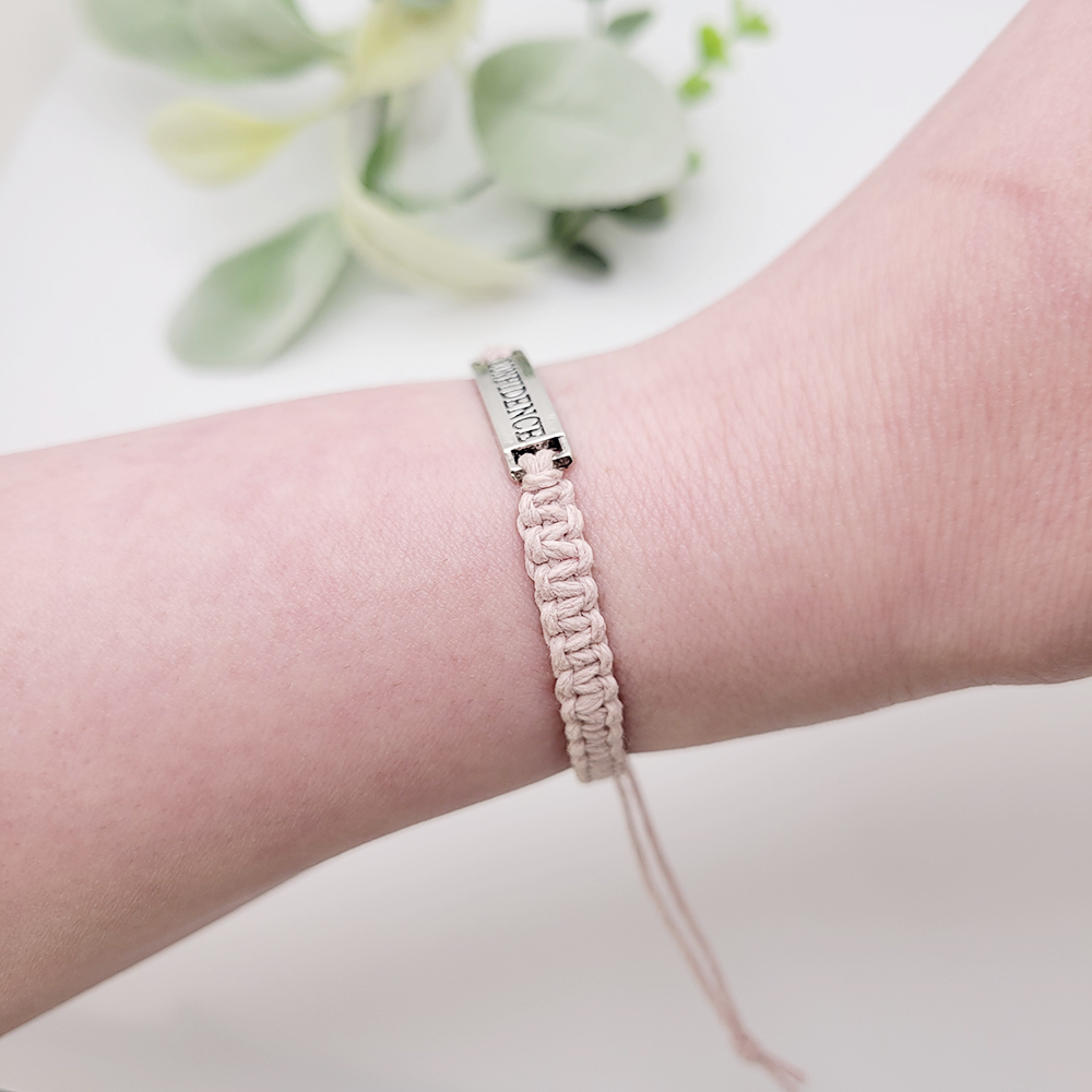 Close-up of handmade cord bracelet with silver Confidence word charm showing knot texture and adjustable fit.