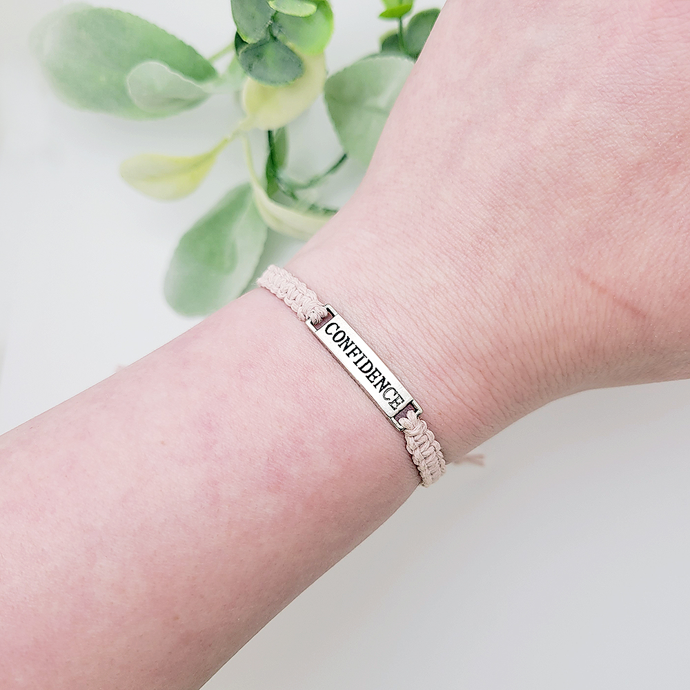 Woman wearing adjustable blush cord bracelet with silver Confidence word charm, minimalist inspirational bracelet.