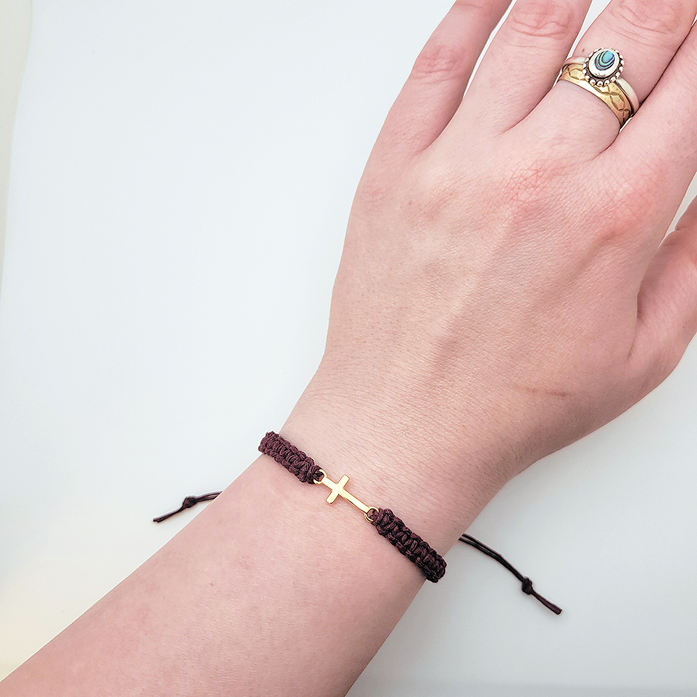 Small gold cross hemp bracelet worn on wrist showing adjustable fit