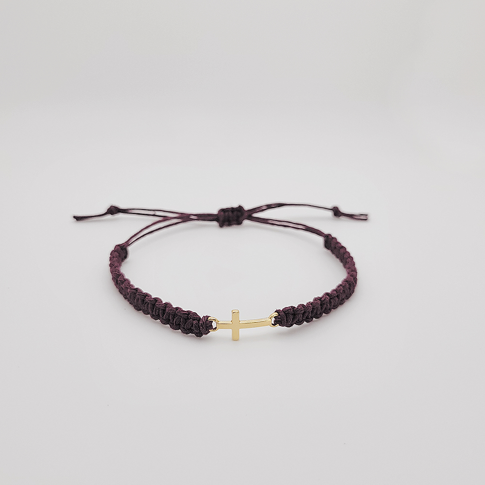 Small gold cross hemp bracelet with adjustable cord on white background