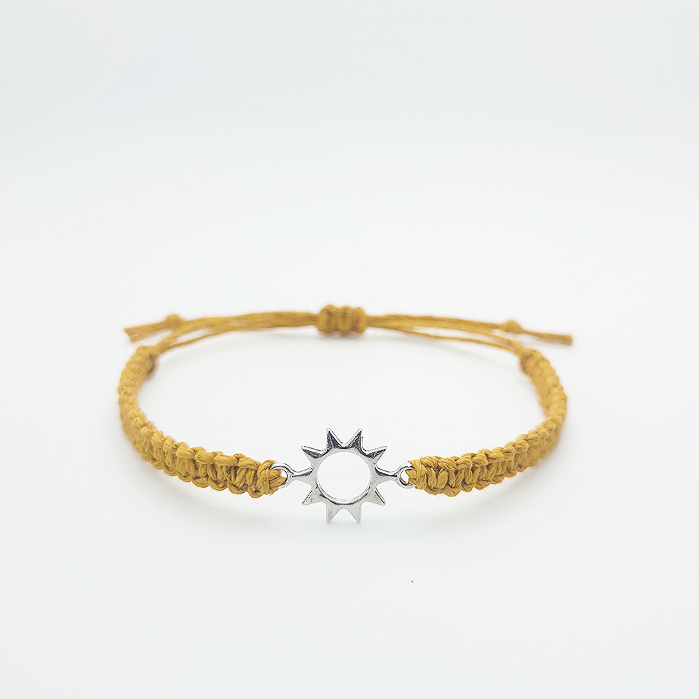 Handmade sun charm hemp bracelet with adjustable mustard cord and silver sun charm on white background
