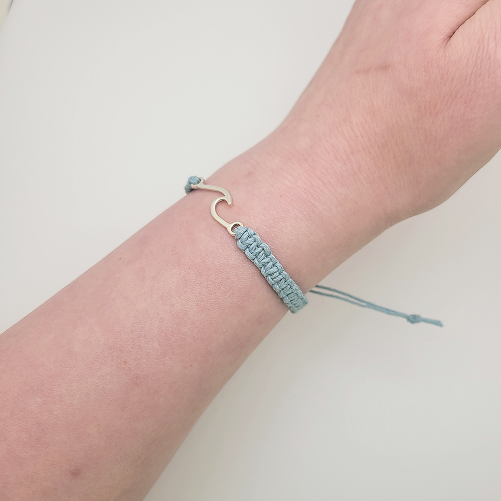 Handmade blue hemp wave bracelet with gold wave charm worn on wrist, adjustable minimalist faith-inspired jewelry