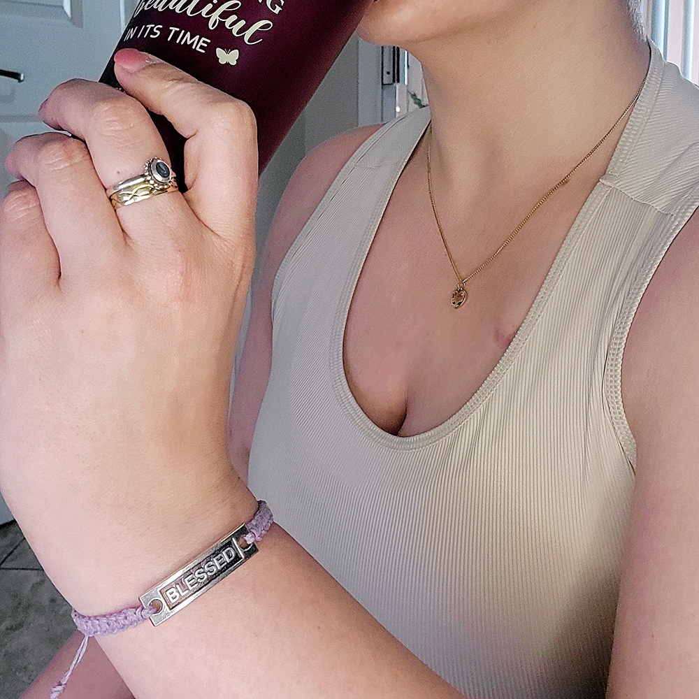 Lilac hemp “Blessed” bracelet worn while holding coffee cup, minimalist Christian jewelry lifestyle photo