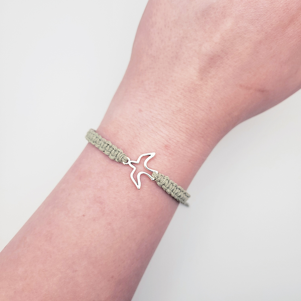 Sage green hemp dove bracelet worn on wrist, adjustable Christian jewelry for everyday wear