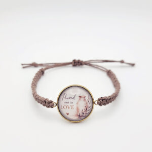 Handmade “Poured Out in Love” hemp bracelet with gold bezel and alabaster jar design on neutral background