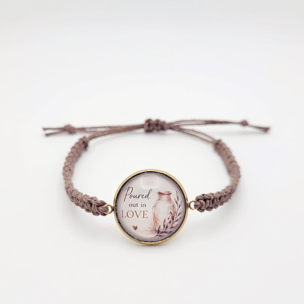 Handmade “Poured Out in Love” hemp bracelet with gold bezel and alabaster jar design on neutral background
