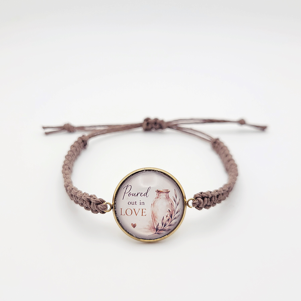 Handmade “Poured Out in Love” hemp bracelet with gold bezel and alabaster jar design on neutral background