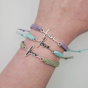 Faith, Hope, and Love handmade hemp bracelet collection in lavender, aqua, and sage green with silver script charms worn on wrist.